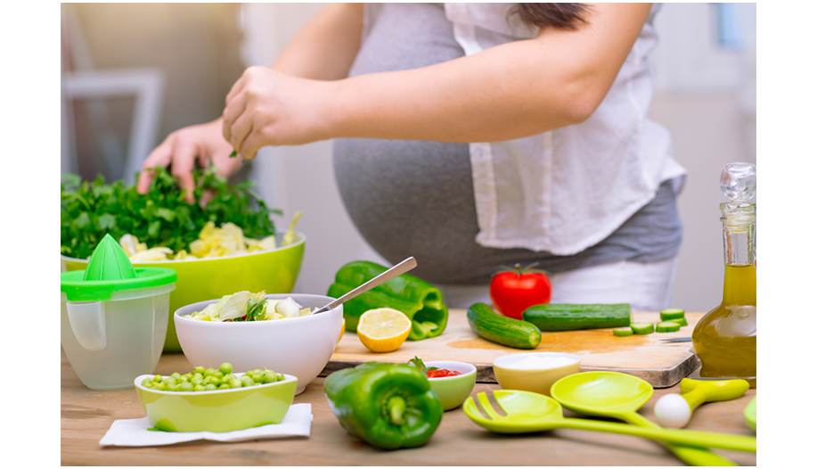 Schwangere Frau bereitet einen grünen Salat zu